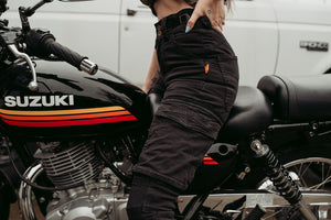 Half body of a woman siting on a motorcycle and wearing black motorcycle cargo pants from moto girl with big pockets s
