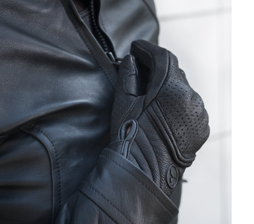 Women closing motorcycle jacket's zipper wearing black leather Shima motorcycle gloves