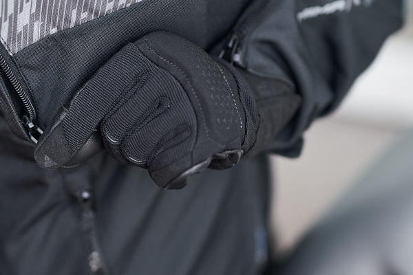 a hand wearing Black leather and textile women motorcycle glove zipping the jacket