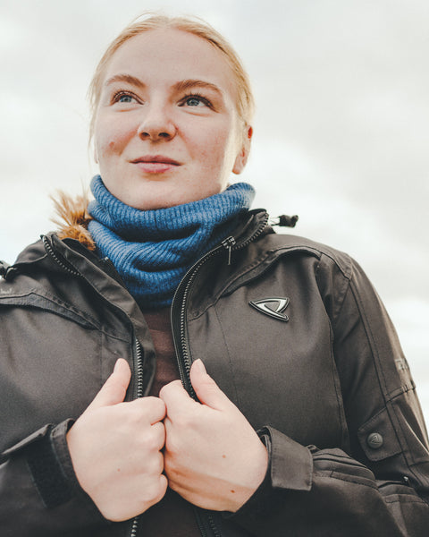 A young woman wearing black lady motorcycle jacket and blue neckwarmer