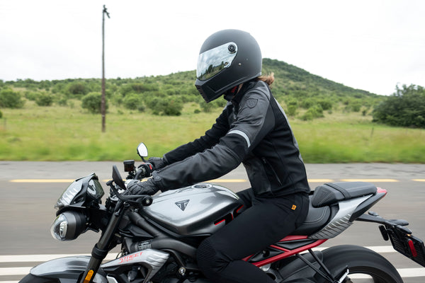 A woman driving a motorcycle wearing Black leather women's motorcycle jacket with reflectors from Moto Girl 