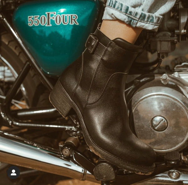 Close up of a woman's foot on the motorcycle break wearing women's black leather motorcycle shoes 