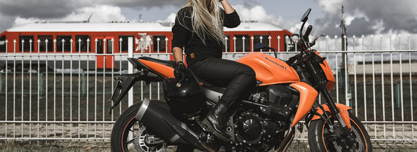 A blond woman on a motorcycle wearing women's black motorcycle jeans Lorica Kevlar from Pando Moto