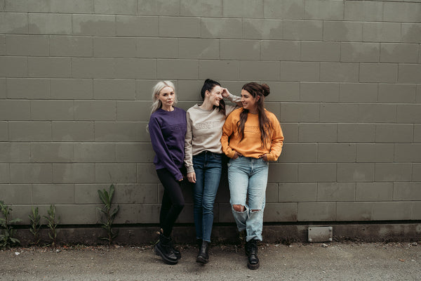 Three young women wearing colourful moto girl lady sweatshirts