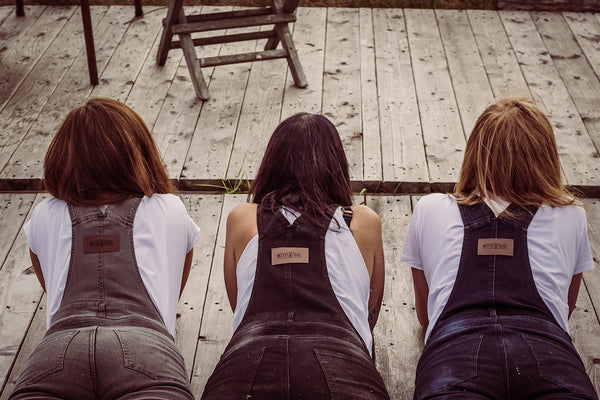 Three women wearing motorcycle overalls laying on the wooden floor