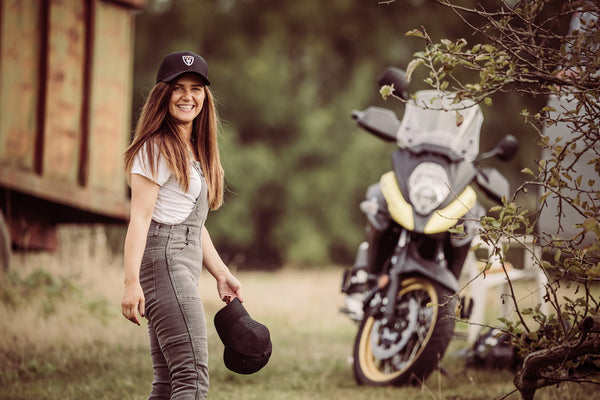 A woman wearing white tshirt and grey motorcycle overall 