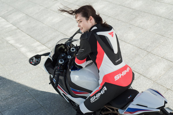 A woman on a motorcycle wearing Women's racing suit MIURA RS in black, white and fluo from Shima 