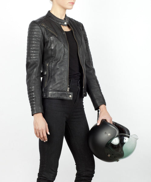 A woman holding a helmet and wearing Women's black leather motorcycle jacket modern classic style from Black arrow label