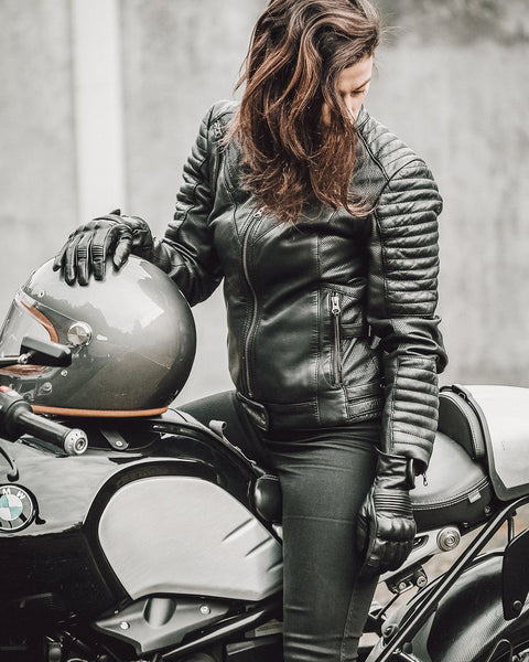 A woman on a motorcycle wearing Women's black leather motorcycle jacket modern classic style from Black arrow label