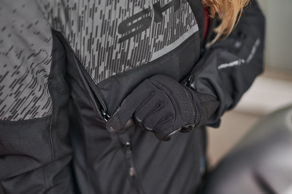 a hand unzipping the ventilation panel on the grey women's motorcycle jacket from SHIMA