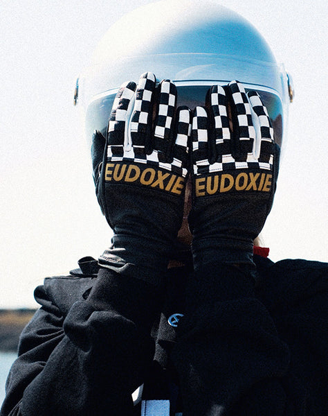 A woman covering her face with her palms, wearing Black and white chessboard motives women's leather motorcycle gloves from Eudoxie