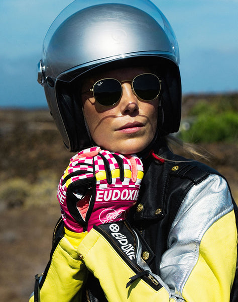 A woman putting on her helmet wearing Ride like a Girl pink, black and yellow women's motorcycle gloves from eudoxie