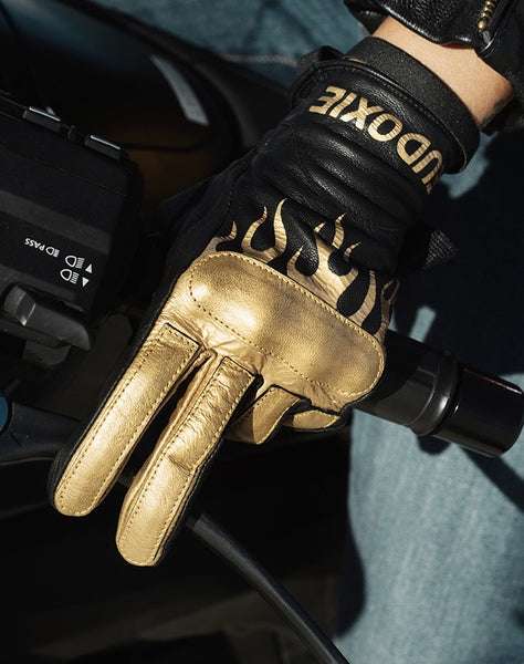 Woman's hand on a throttle wearing black Eudoxie mc glove with golden flames 
