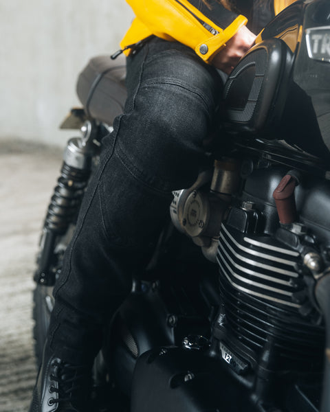 Et ben af en kvinde, der sidder på en motorcykel og iført sorte lady mc jeans