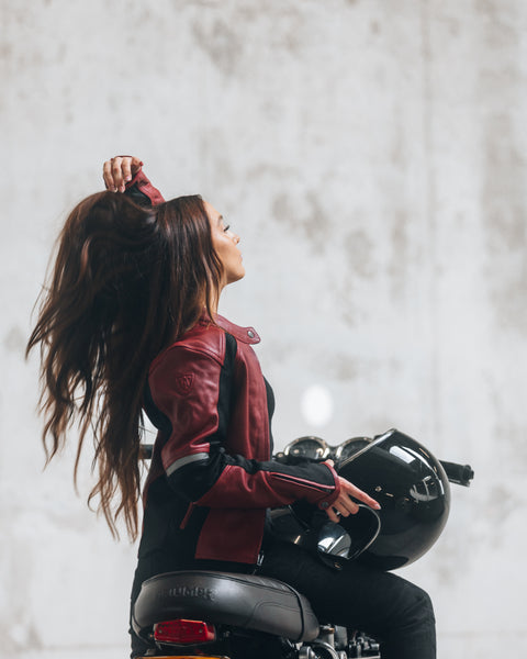 En ung kvinde på sin motorcykel iført en rød motorcykeljakke til damer